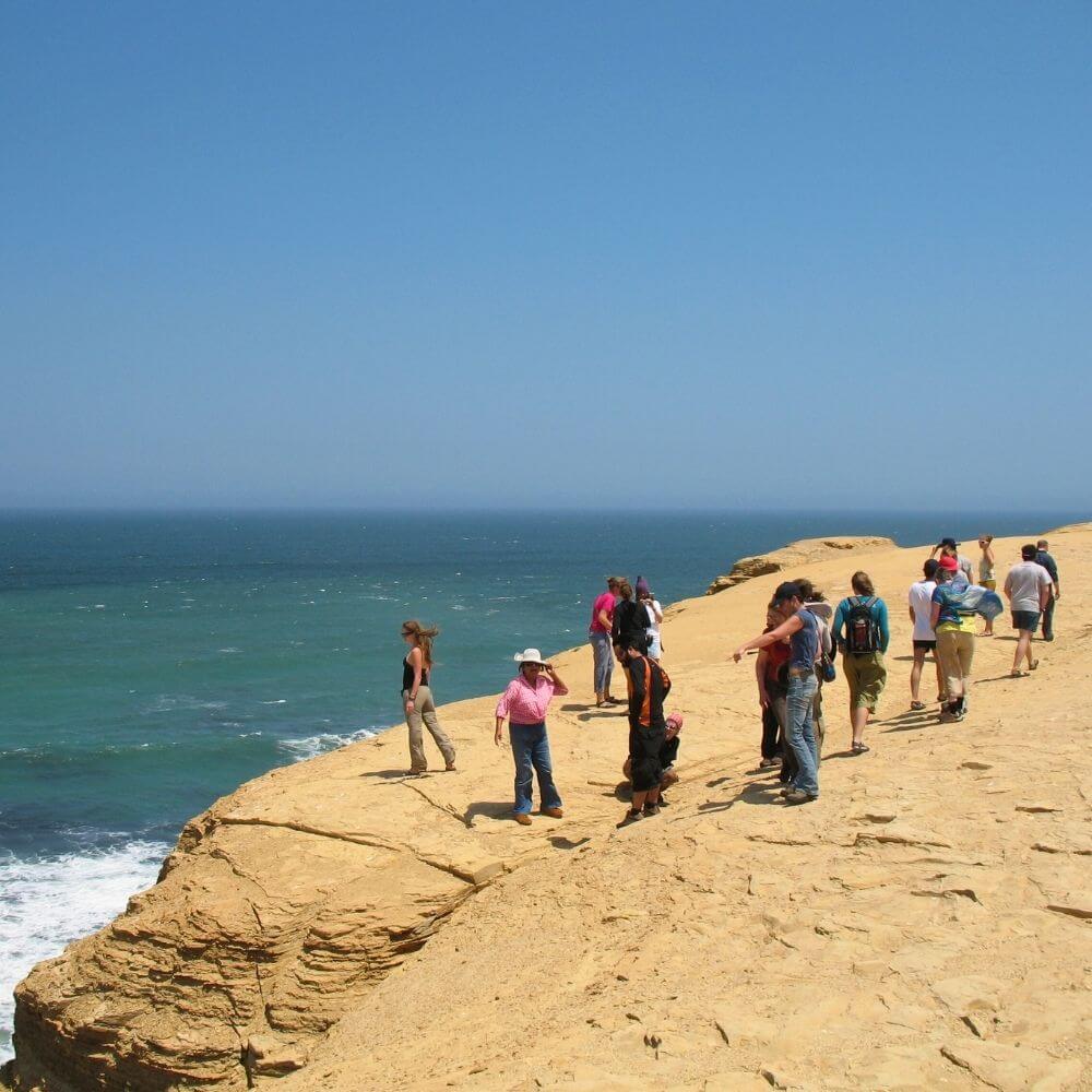Travelers exploring the dramatic coastal cliffs of the Paracas Peninsula during a Paracas and Nazca Lines Tour from Lima.