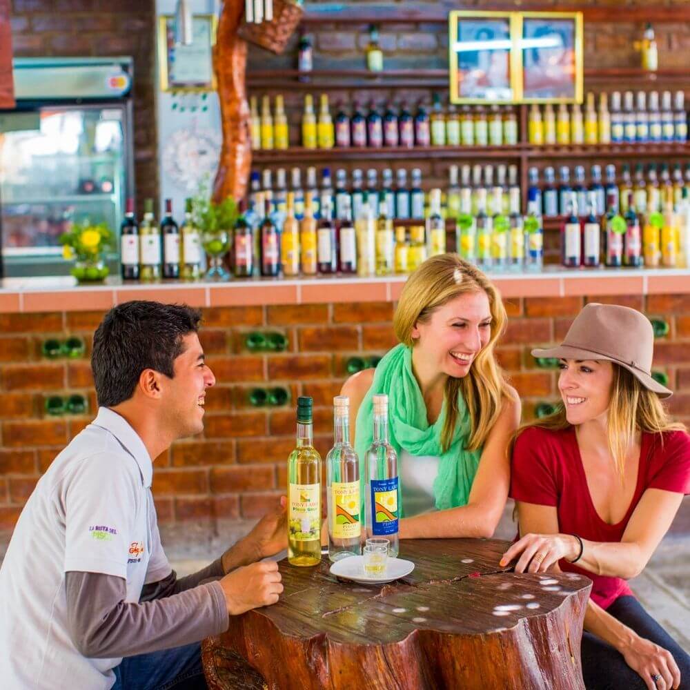 Tourists enjoying a traditional Pisco tasting experience at a vineyard in Ica.