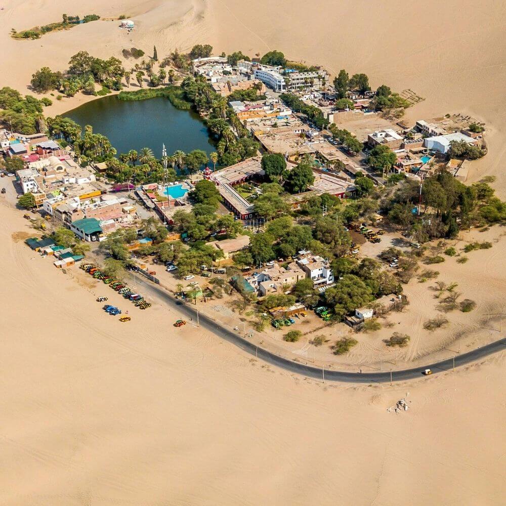 Aerial view of the Huacachina Oasis surrounded by giant sand dunes in the Peruvian desert near Ica.