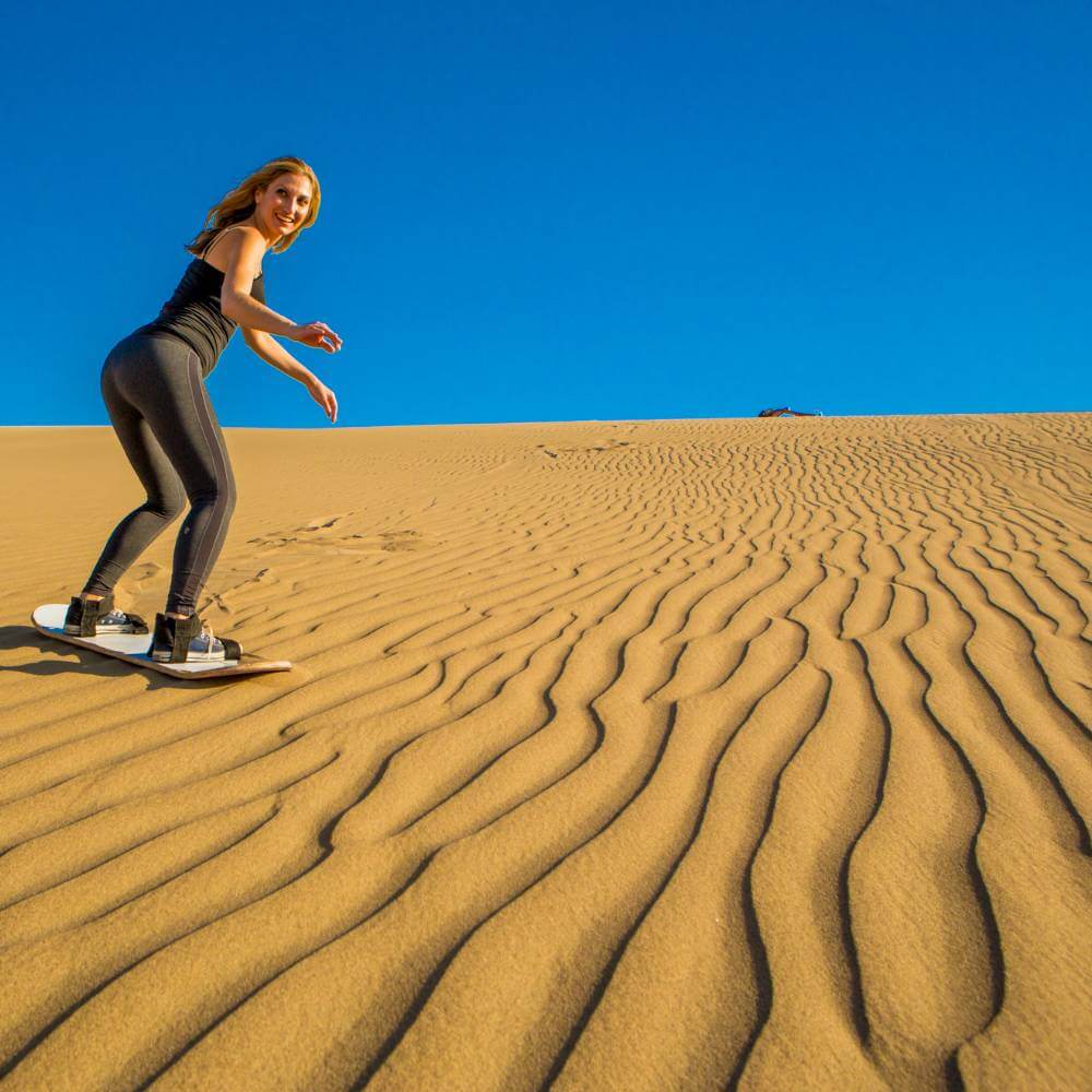 Traveler enjoying sandboarding on the dunes of Huacachina in Ica Peru