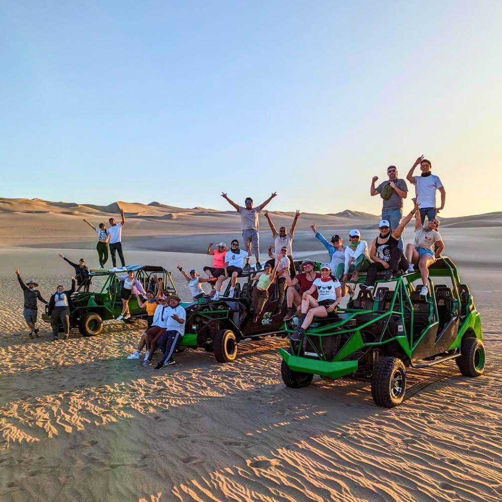 Group of travelers enjoying a dune buggy tour across the massive sand dunes of Huacachina in Peru.