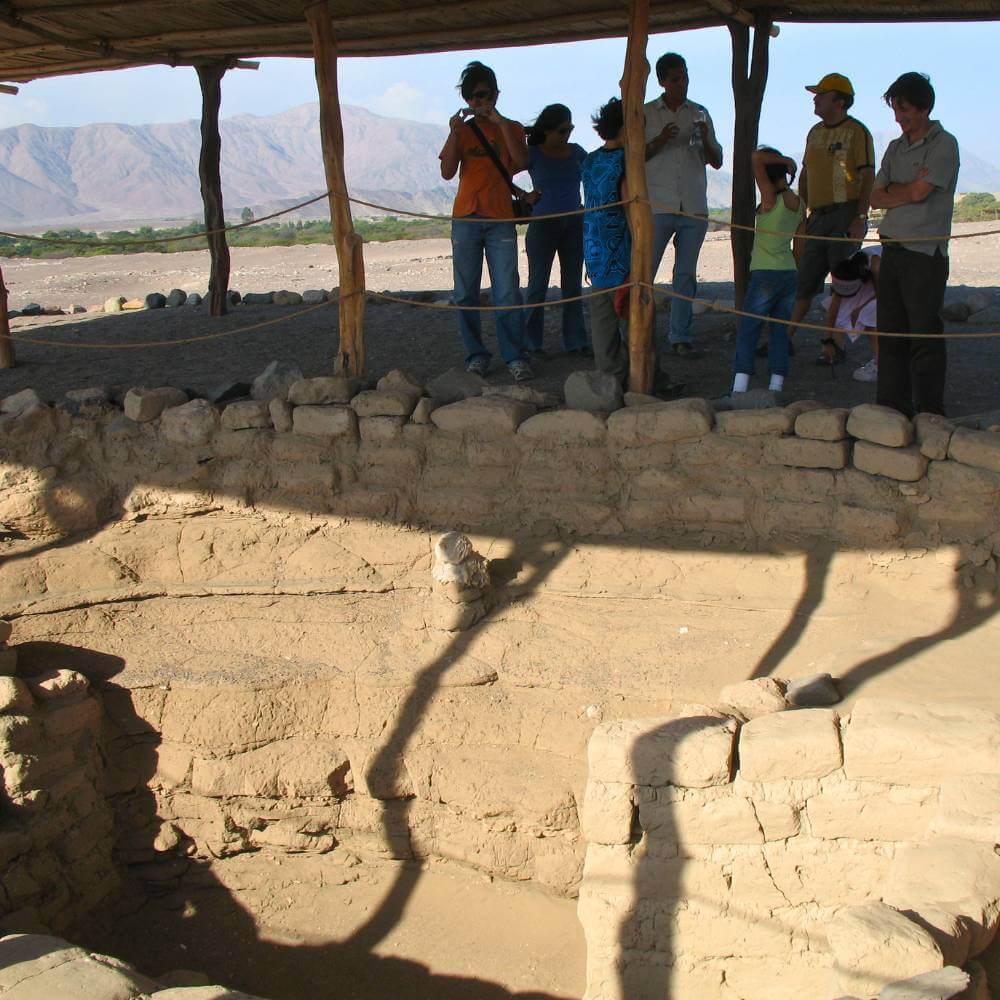 Tourists exploring ancient tombs at the Chauchilla Cemetery during a guided archaeological tour in the Nazca desert of Peru.