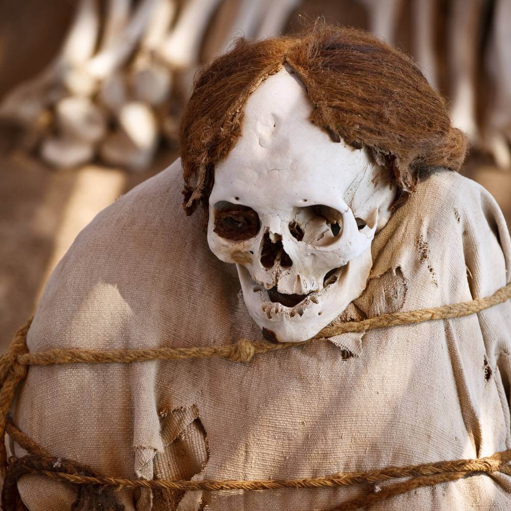 Ancient Nazca mummy with preserved hair and textiles at the Chauchilla Cemetery in the Peruvian desert.