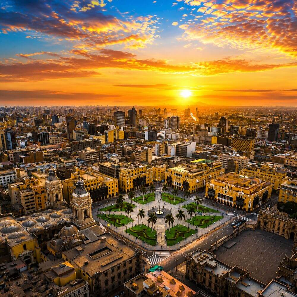Panoramic aerial view of Lima Historic Center at sunset featuring Plaza Mayor, colonial landmarks, and the skyline of Peru's capital city.