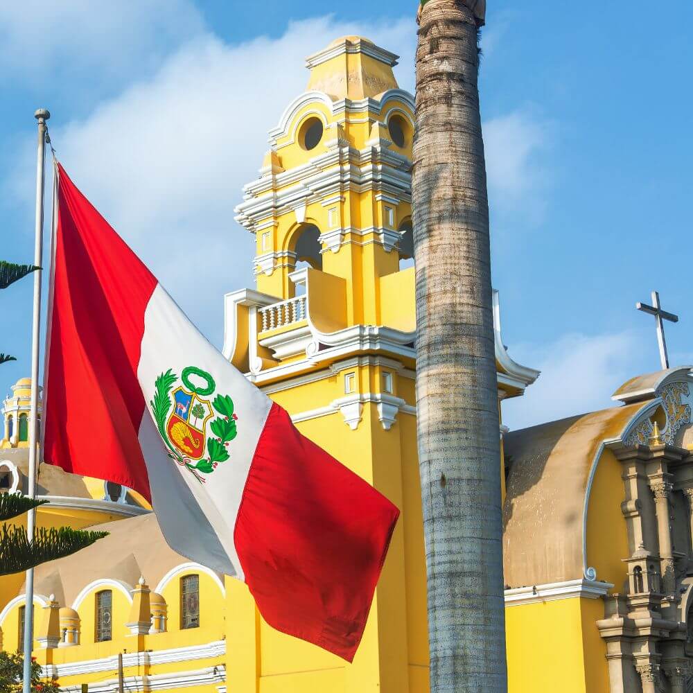 Peruvian flag waving beside a historic colonial church in Lima, showcasing the cultural heritage of Peru.