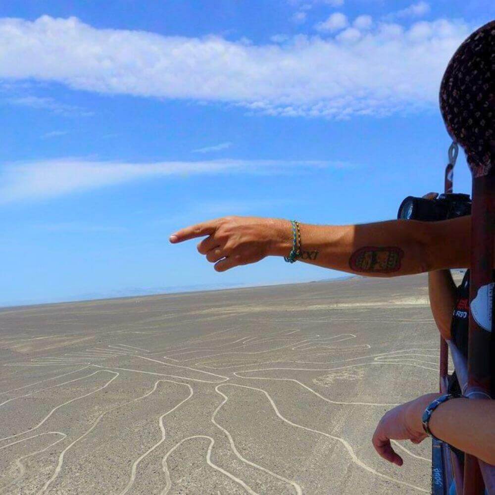Tourist pointing at the Nazca Lines from a sightseeing aircraft during a full-day tour from Lima.