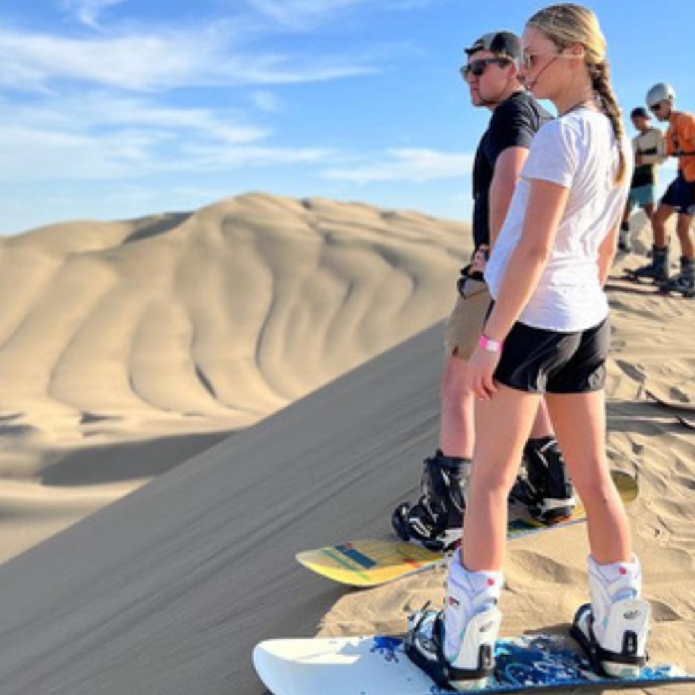 Travelers preparing for sandboarding on the massive dunes of Huacachina Oasis in Peru
