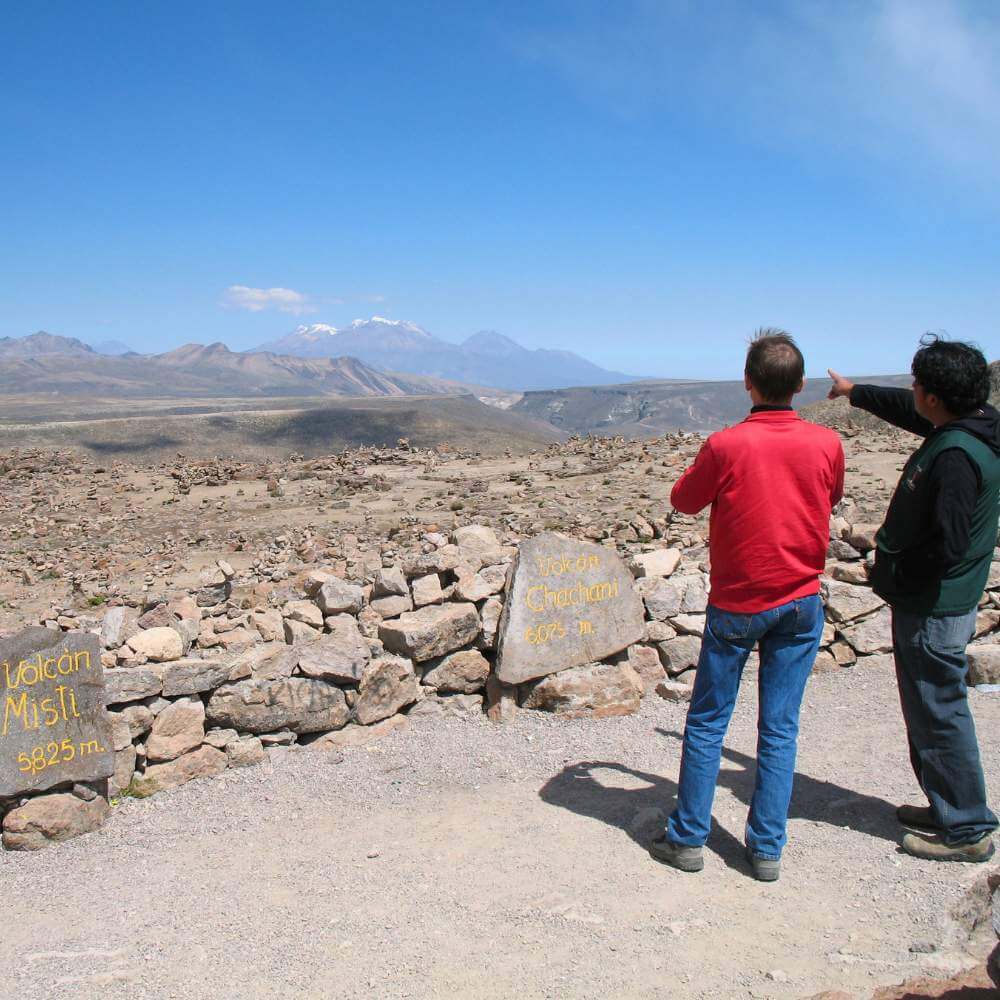 Travelers admiring the snow-capped volcanoes from Patapampa, the highest viewpoint on the Colca Canyon Tour from Arequipa to Puno.