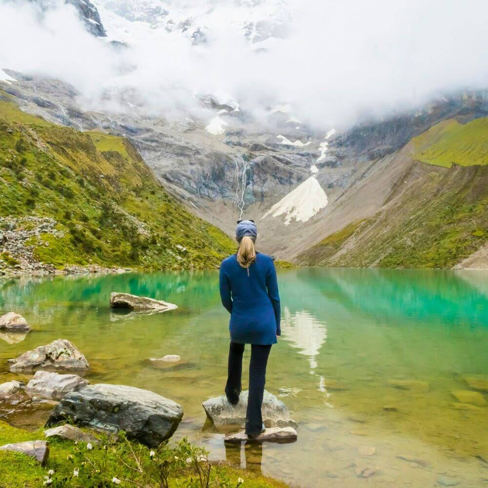 Traveler standing at the edge of Humantay Lake with panoramic views of the Humantay Glacier during the Humantay Lake Trek from Cusco.