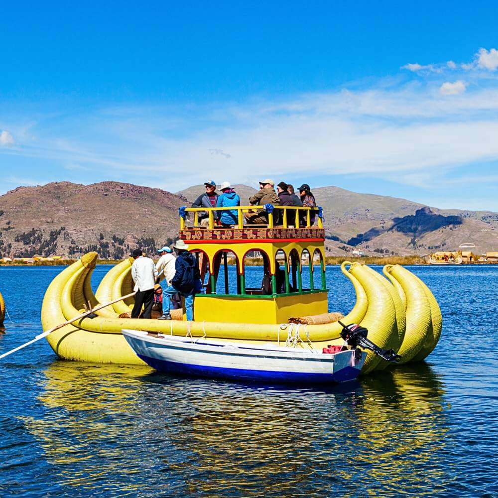 Traditional totora reed boat carrying visitors across Lake Titicaca during a Lake Titicaca Full Day Tour to the Uros Floating Islands.