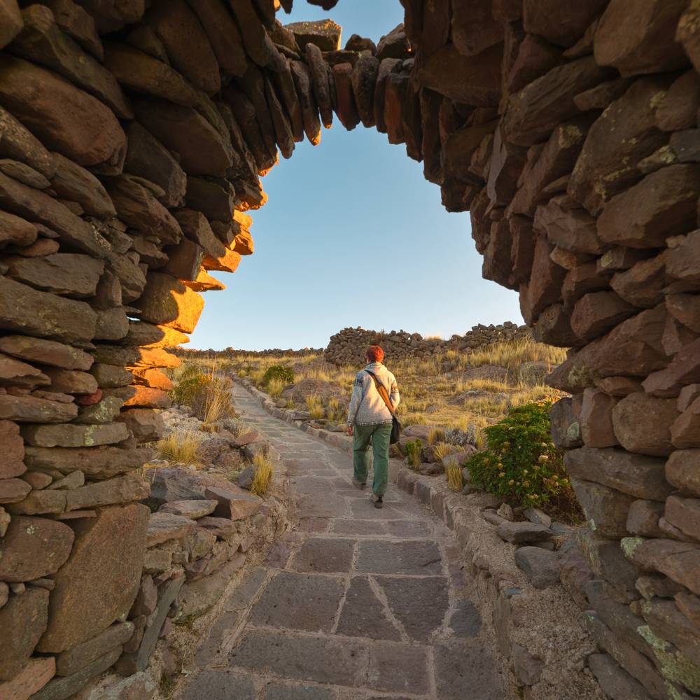 Traveler walking through ancient stone ruins on Amantani Island during a Lake Titicaca Homestay Tour in Peru.