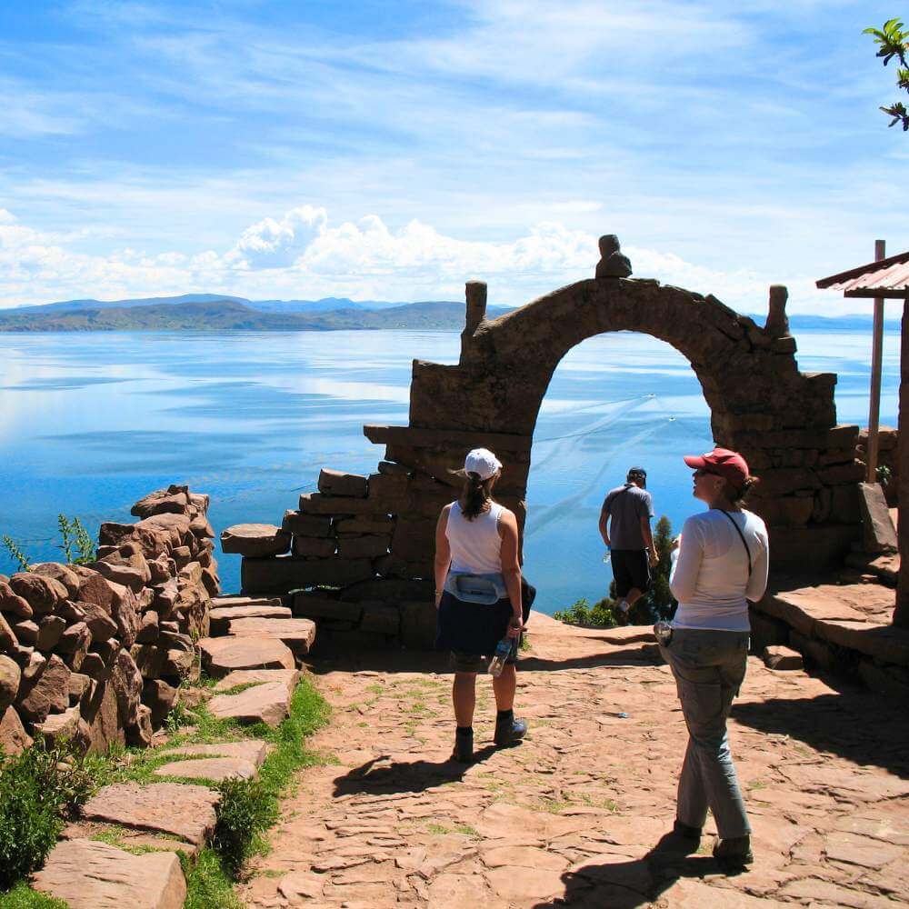 Travelers enjoying panoramic views from Taquile Island overlooking the crystal-clear waters of Lake Titicaca, Peru.