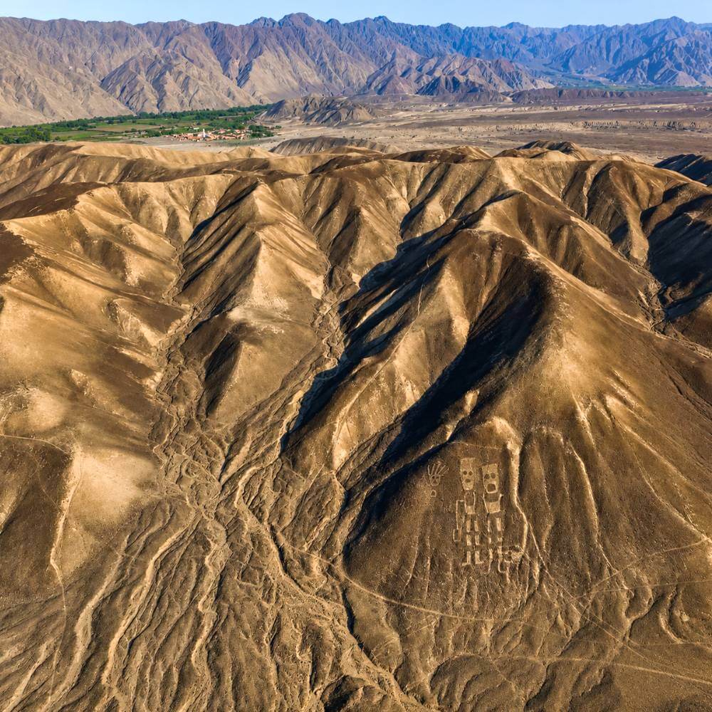 Aerial view of ancient twin humanoid geoglyphs carved into a hillside in the Palpa region of southern Peru.