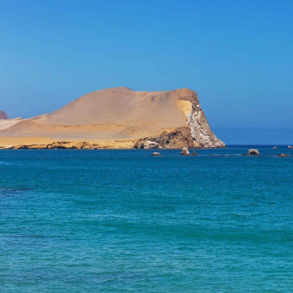 Panoramic view of Paracas Bay featuring turquoise waters, desert cliffs, and dramatic coastal scenery in Peru.