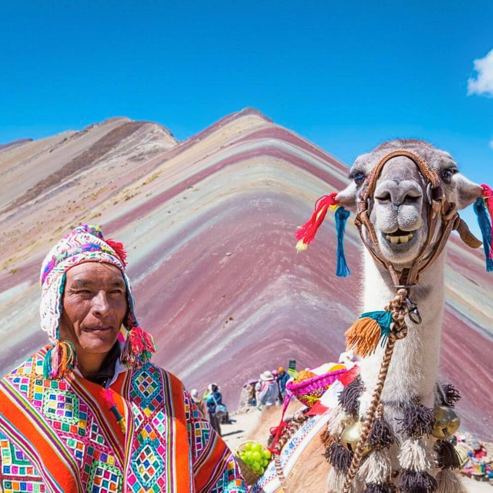 Local Andean man and decorated llama at Rainbow Mountain Vinicunca viewpoint in the Peruvian Andes near Cusco.