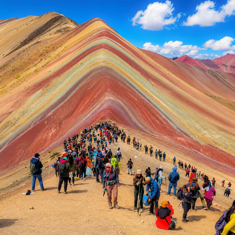 Hikers reaching the famous Rainbow Mountain viewpoint surrounded by the colorful mineral-striped slopes of Vinicunca, Peru.