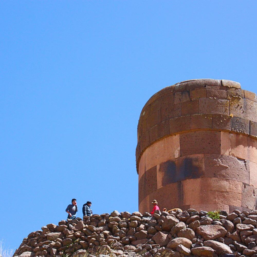 Visitors exploring the ancient Chullpas of Sillustani, impressive pre-Inca burial towers overlooking the Andean highlands near Puno, Peru.