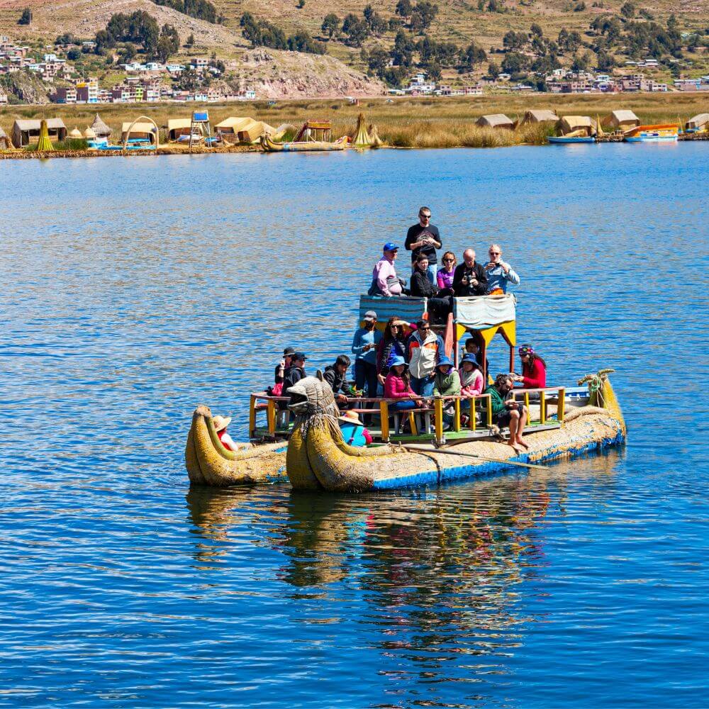 Travelers enjoying a traditional totora reed boat ride on Lake Titicaca during the Tour to Uros Floating Islands in Peru.