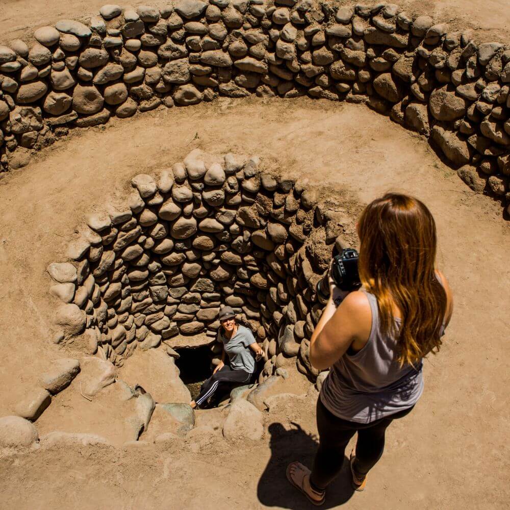Visitors descending into a spiral puquio at the Cantayo Aqueducts near Nazca, Peru, part of the ancient Nazca hydraulic system.