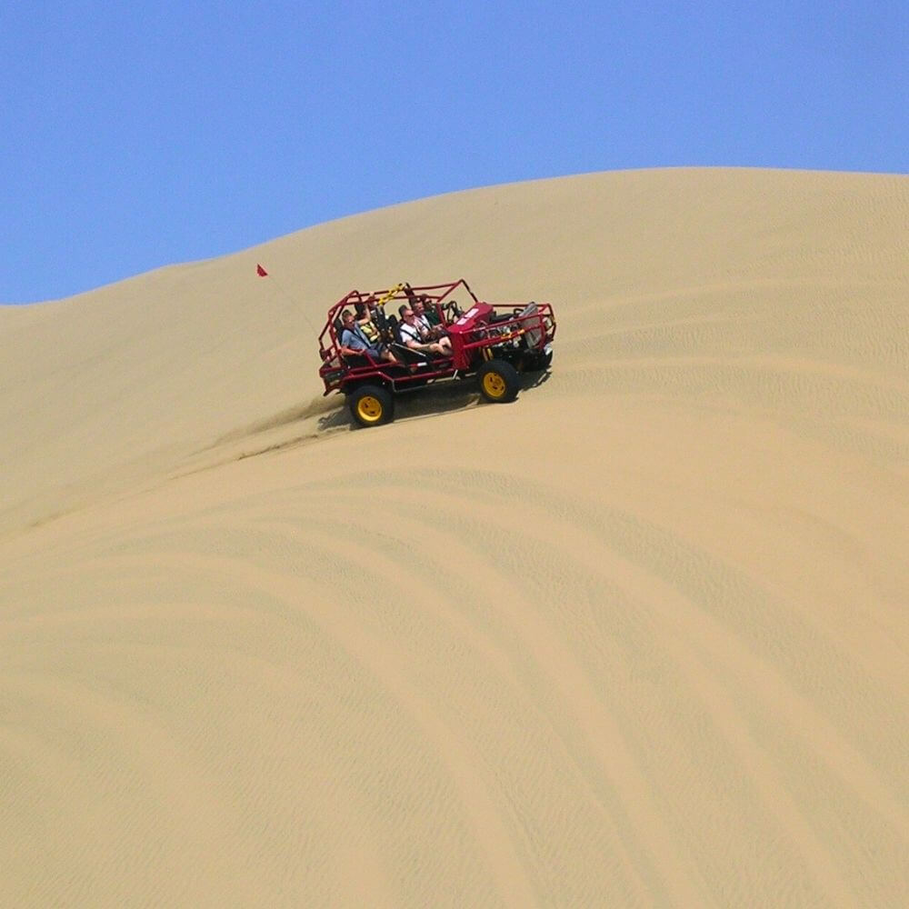 Tourists riding a dune buggy across the giant sand dunes of Huacachina in Peru.