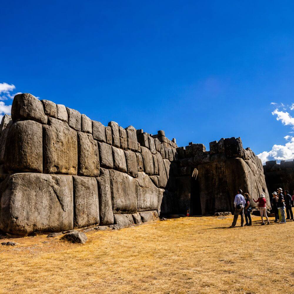 Visitors exploring the massive stone walls of Sacsayhuamán Fortress during a Cusco City Tour in Peru.