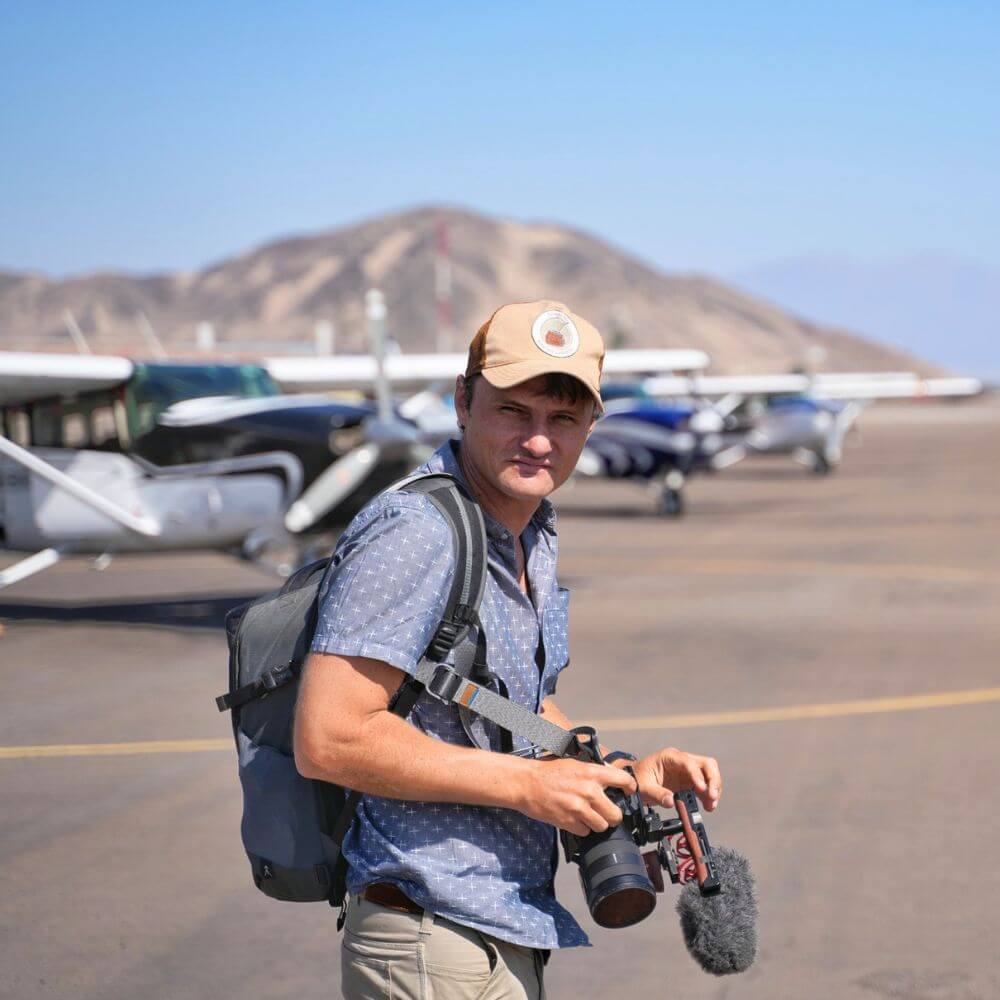 Traveler with camera standing beside aircraft at Nazca Airport before a Nazca Lines scenic flight in Peru.