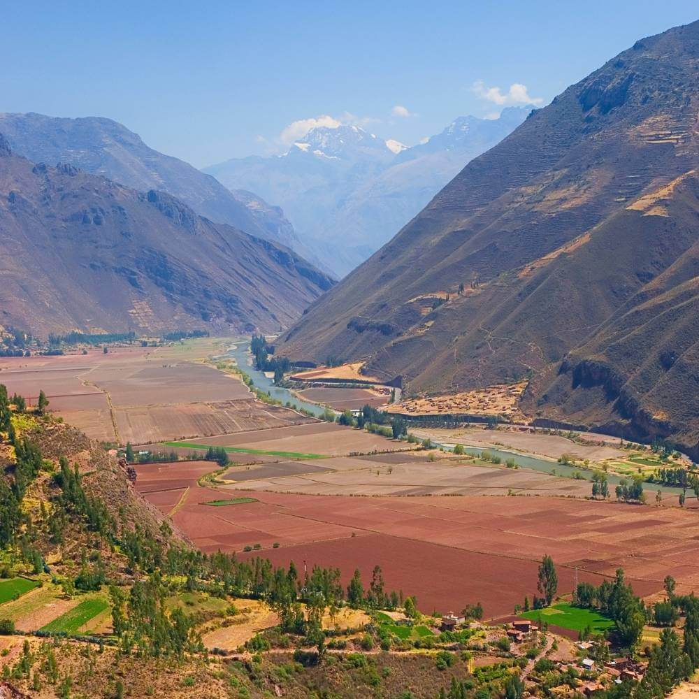 Panoramic view of the Sacred Valley of the Incas with the Urubamba River, fertile farmlands, and towering Andes Mountains near Cusco.