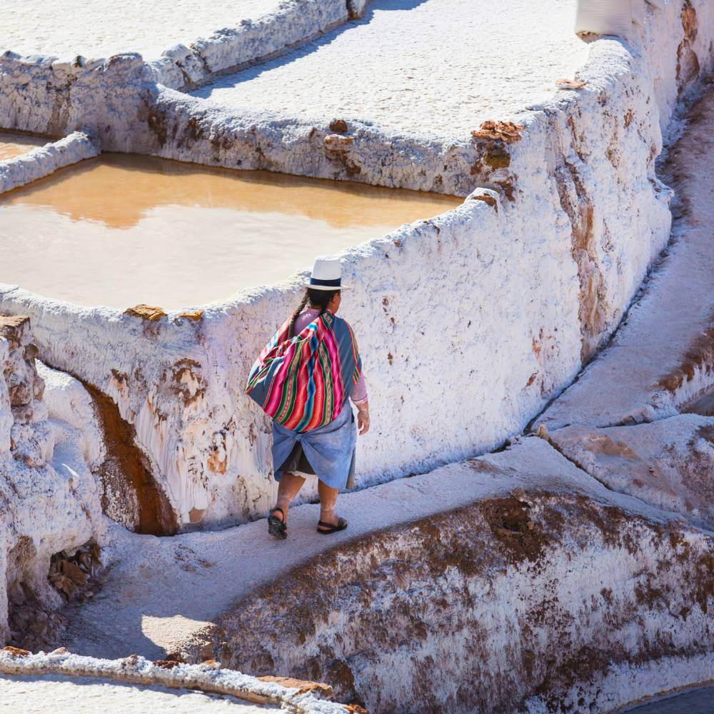 Local worker walking through the historic Maras Salt Mines, where traditional salt harvesting continues in the Andes of Peru.