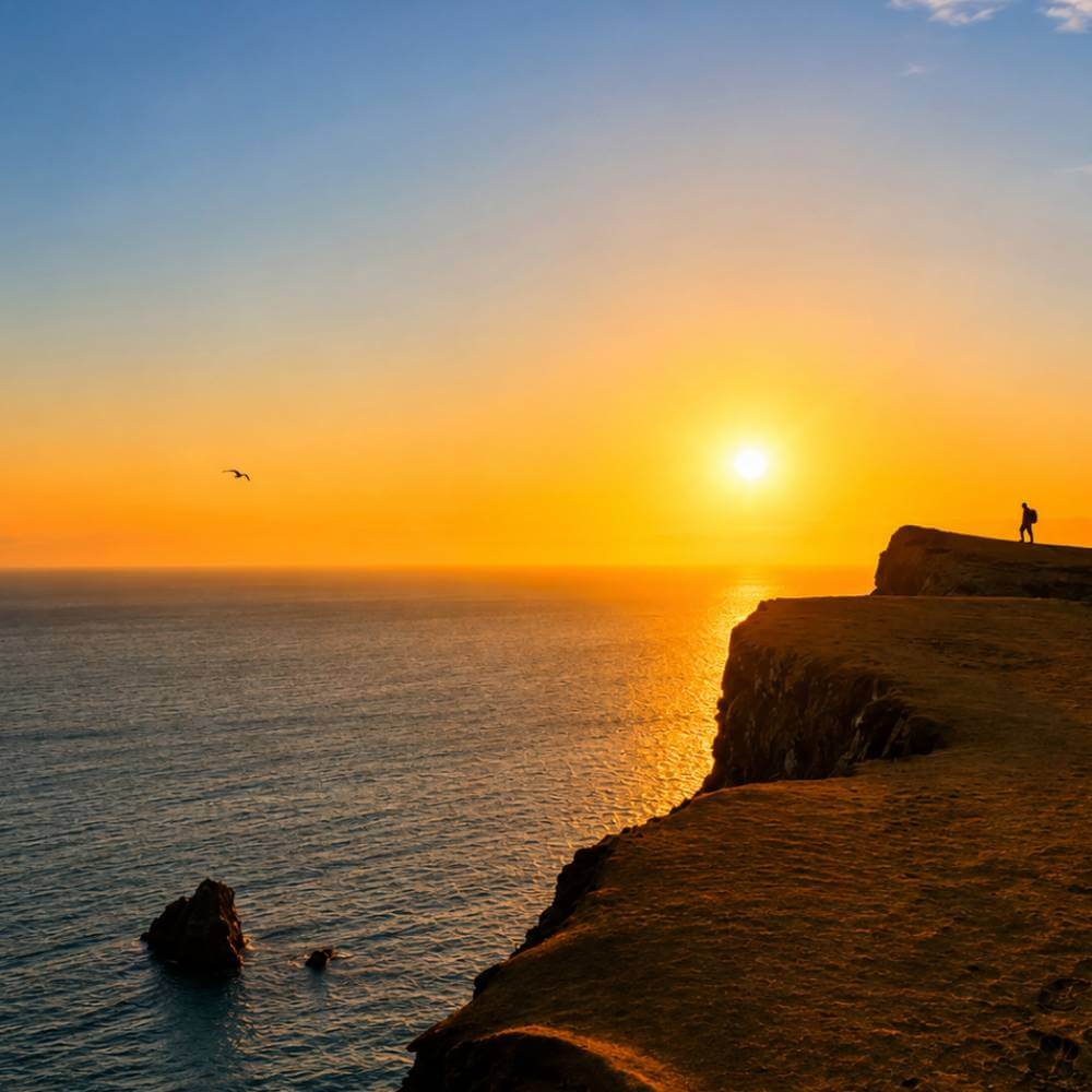 Traveler enjoying a spectacular Pacific Ocean sunset from the coastal cliffs during the Golden Shadows Trek in Paracas, Peru.