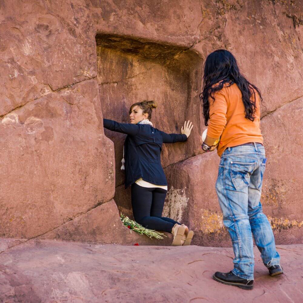 Traveler standing inside the carved stone doorway of Aramu Muru, the legendary Gate of the Gods near Lake Titicaca in Puno, Peru.