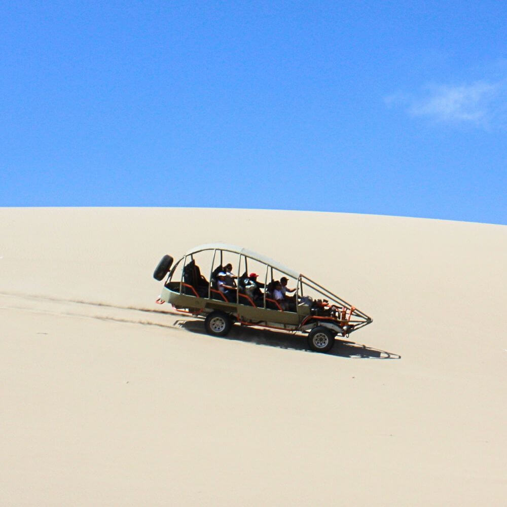 Travelers enjoying a 4x4 dune buggy adventure during the Oasis Morón Tour from Paracas across Peru's spectacular coastal desert.