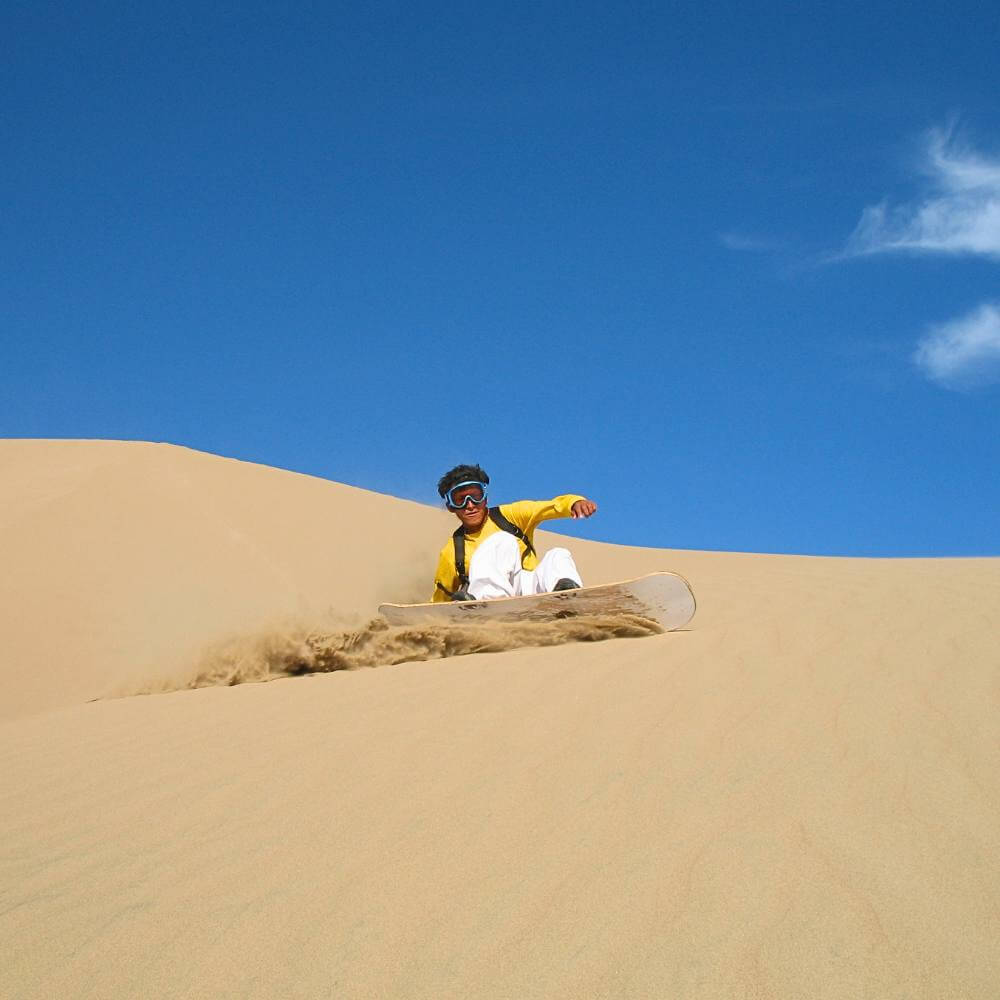 Traveler sandboarding down the massive slopes of Cerro Blanco near Nazca, Peru.