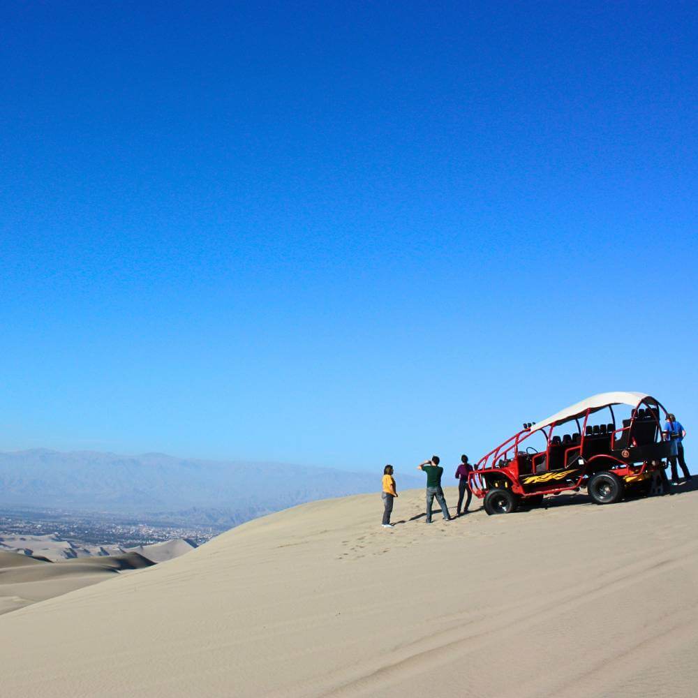 Off-road dune buggy parked on a scenic viewpoint overlooking the Huacachina Desert in Peru.