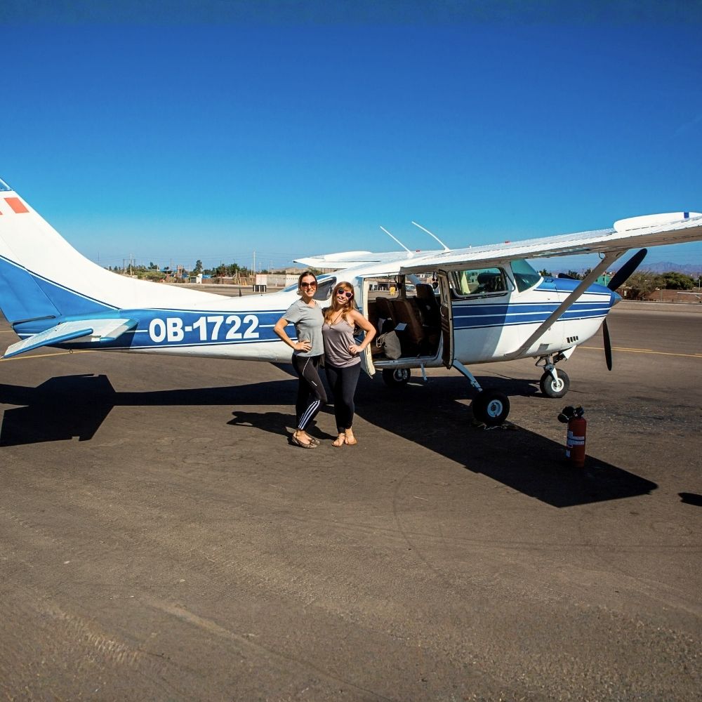 Travelers posing beside a sightseeing aircraft at Nazca Airport before a Nazca Lines flight from Lima by bus.