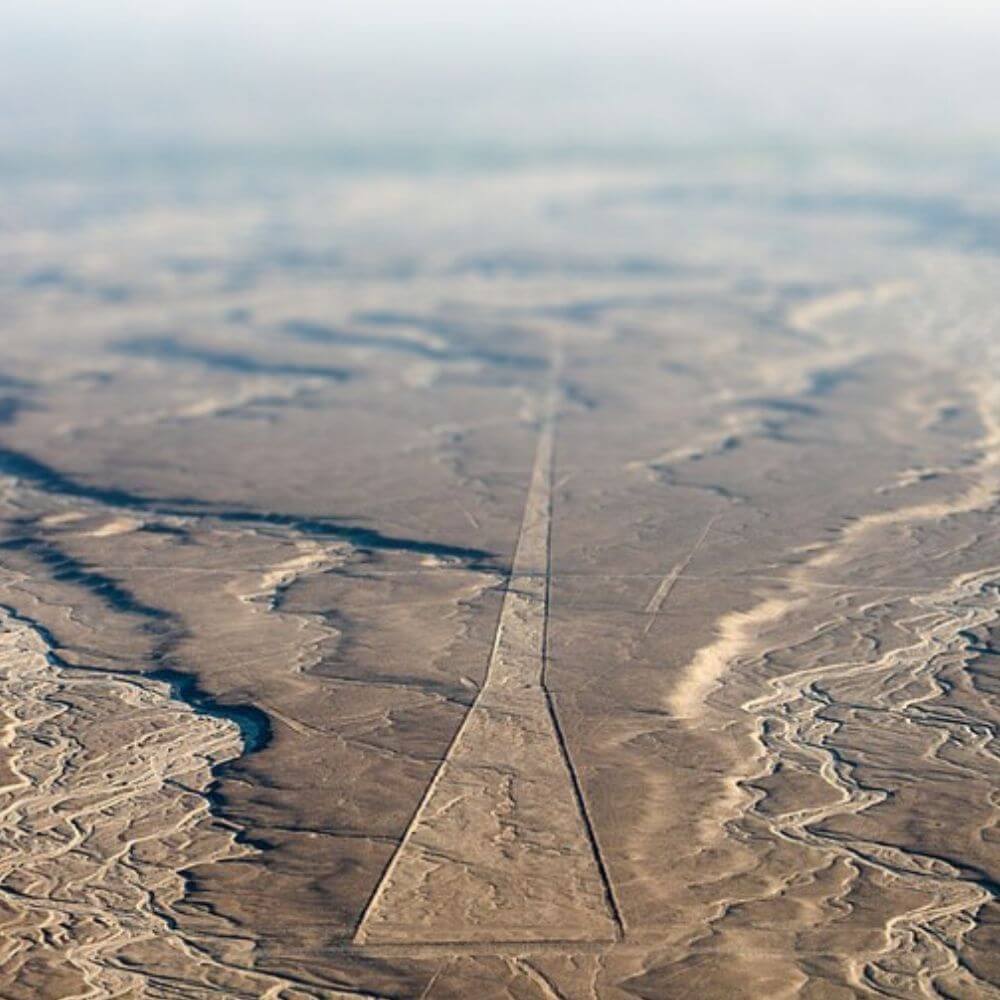 Massive trapezoid and geometric lines stretching across the Nazca Desert, viewed during a scenic flight.
