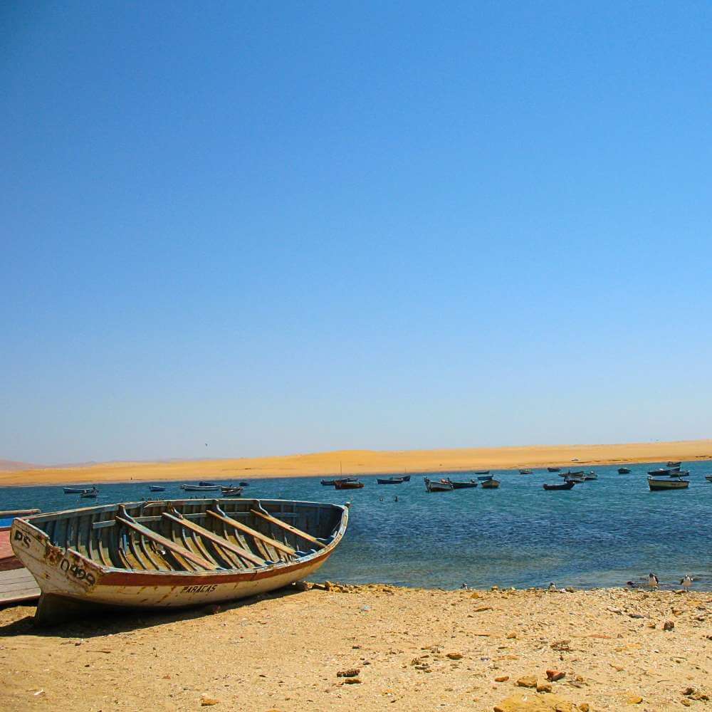 Traditional fishing boats resting along the peaceful bay of Lagunillas Fishing Village in the Paracas National Reserve, Peru.