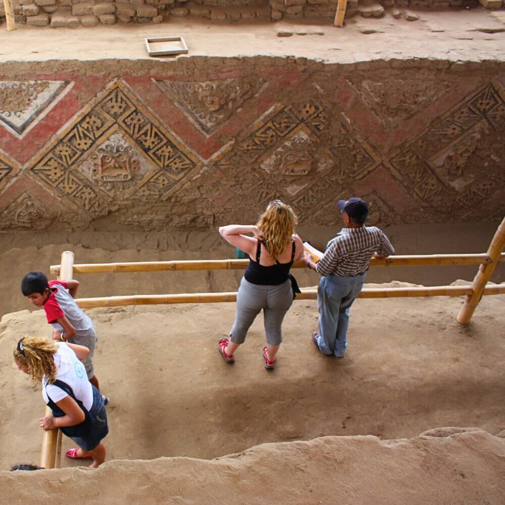 Travelers exploring the colorful ceremonial murals inside Huaca de la Luna during a guided Moche Temples tour in Trujillo, Peru.