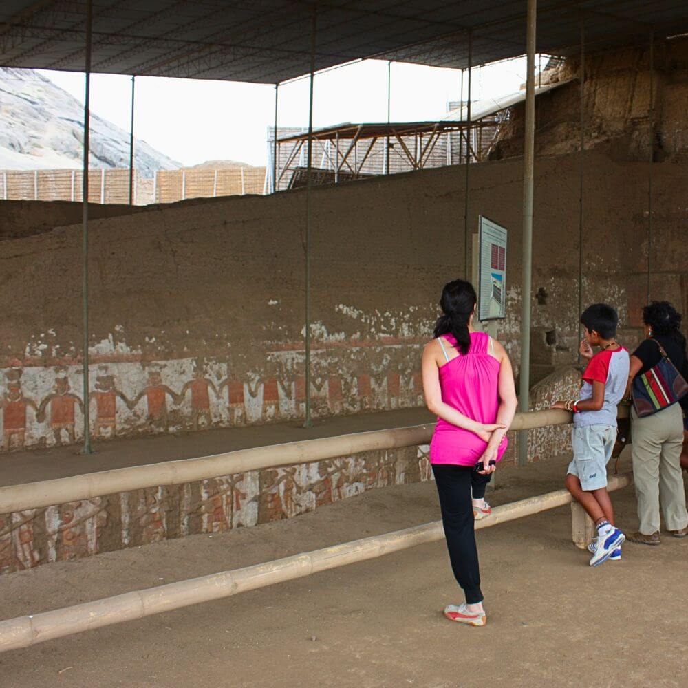 Visitors admiring original Moche ceremonial friezes inside Huaca de la Luna archaeological site near Trujillo, Peru.