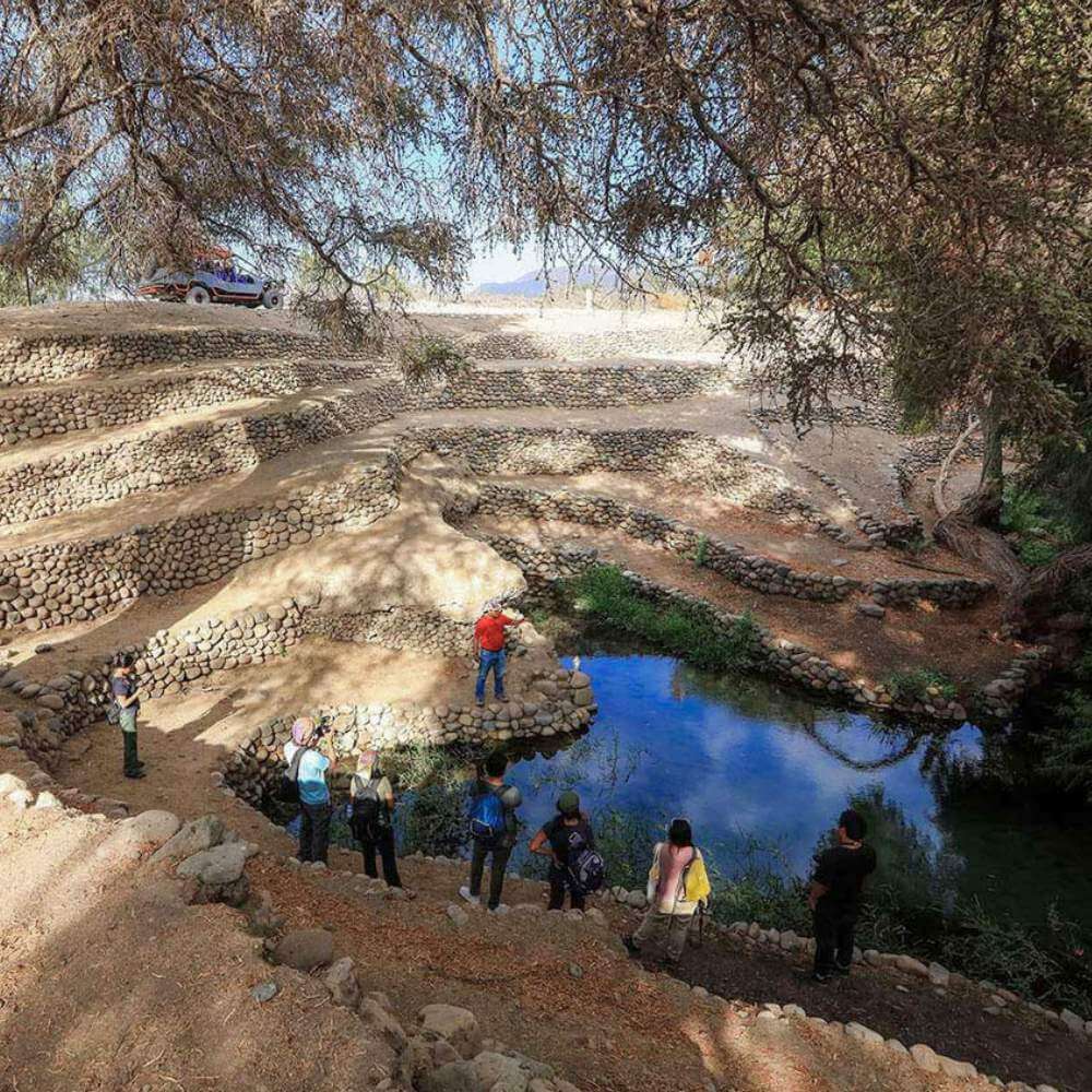 Visitors exploring the ancient Ocongalla Aqueducts during the USAKA DESERT TOUR near Nazca, Peru, surrounded by remarkable pre-Inca hydraulic engineering.