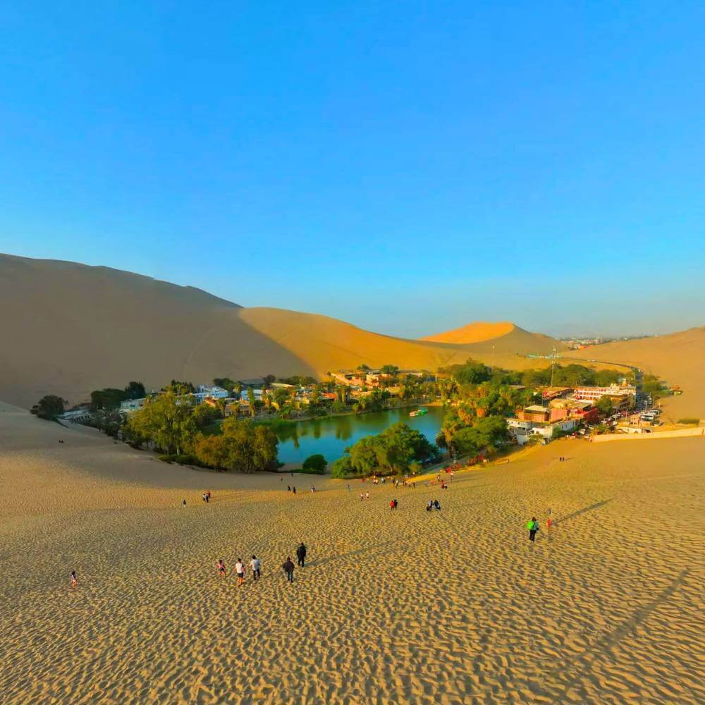Panoramic view of Huacachina Oasis surrounded by golden sand dunes during a 3-day Peru desert adventure.