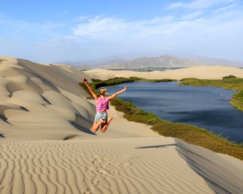 Traveler posing at Oasis Morón with dunes in background.
