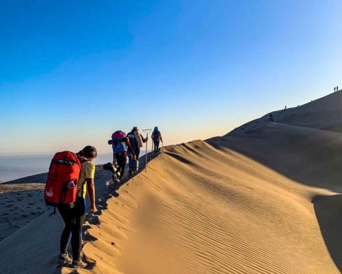 Group hiking on the ridge of Cerro Blanco dune