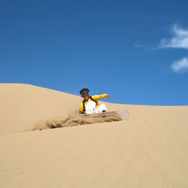 Sandboarder gliding down the steep face of Cerro Blanco dune in Peru