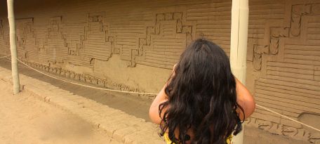 Tourist photographing friezes at Chan Chan archaeological site.