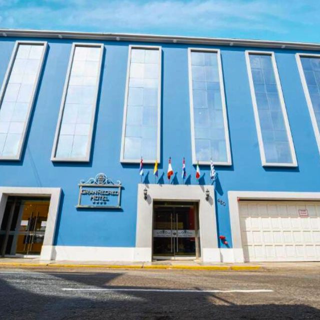 Facade of Gran Recreo Hotel with modern blue exterior and international flags