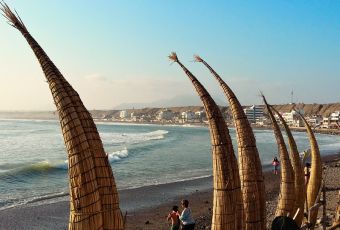 Totora reed boats on the shore of Huanchaco Beach at sunset
