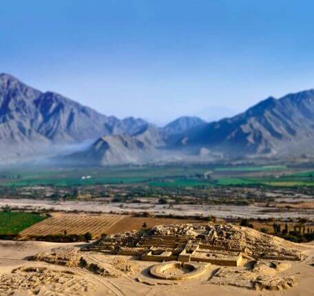 Aerial view of Caral's main pyramid and circular plaza surrounded by mountains