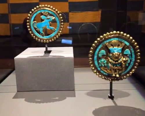 Museum display of Moche earrings with turquoise and gold figures