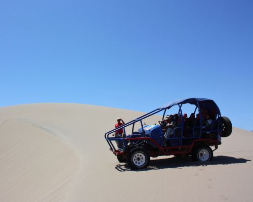 4x4 dune buggy climbing a steep sand dune on the Usaka Desert Tour